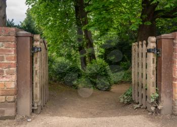 Wood gates leading into a dirt path in a dark forest or wood