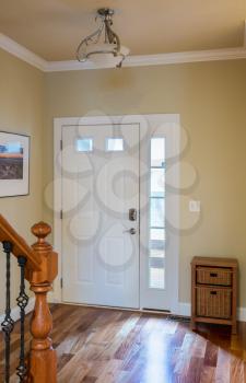 Closed front door leading onto wood steps with lobby or hall with hardwood flooring