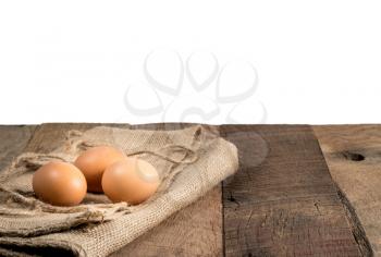 Easter background with brown organic eggs arranged on burlap sack on rustic wooden table with isolated background