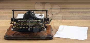Antique portable typewriter with non qwerty keys and copy space on white paper on desk