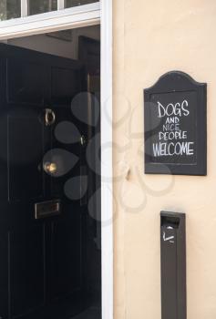Humorous sign on blackboard outside pub saying dogs welcome with nice people