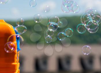 Childrens toy soap bubble blower creating bubbles on sunny summer day
