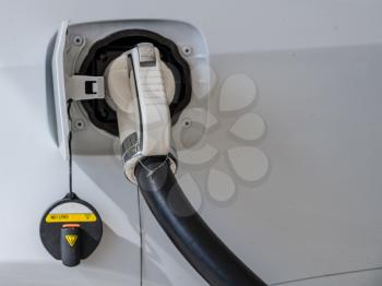 Cable plugged into car at electric vehicle charging station at motorway rest stop