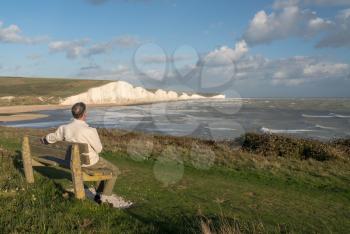 Senior man looks at waves by the chalk cliffs of the Seven Sisters at Cuckmere Haven