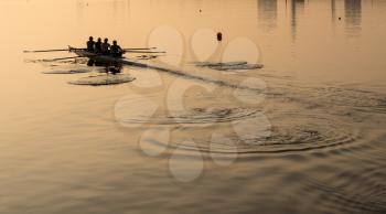 Sunrise lights up team of four rowers in canoe practicing in London Docklands