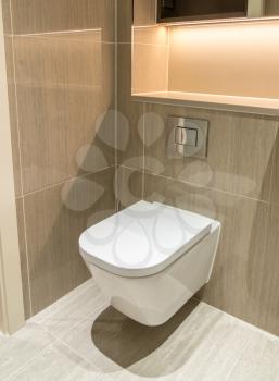 Modern toilet or WC in clean apartment or flat with white porcelain and tiled walls and floor