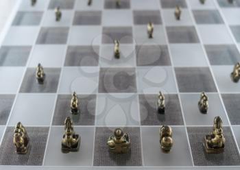 Historic old chinese metal chess pieces on modern glass chessboard