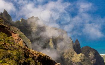 Fluted rocks of the Na Pali mountains through the clouds from Kalalau lookout on Kauai