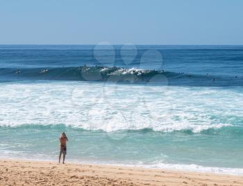 Many surfers waiting for big wave in the sea at Banzai Pipeline on north coast of Oahu, Hawaii
