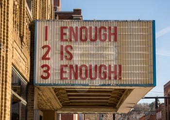 Mockup of movie cinema billboard with message of Enough is enough on the marquee sign in downtown street