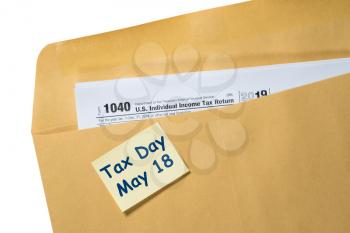Printed Form 1040 for income tax return in brown envelope with reminder for May 18 tax day due to Covid-19 virus delay