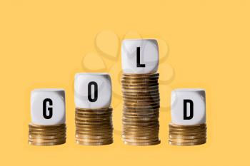 Sudden falling value in investment plan in price of GOLD with blocks on stacks of gold coins on golden background