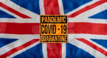 Pandemic sign warning of quarantine due to Covid-19 or corona virus in the UK using a british flag in the background