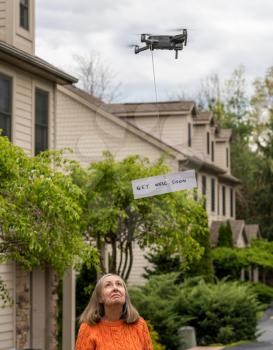 Flying drone delivering a get well soon message touch free to a quarantineed grandmother during coronavirus epidemic