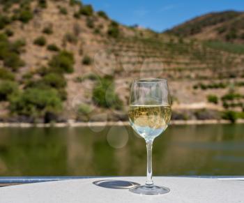 Glass of white wine for tasting on deck of cruise boat on the river in the Douro valley in Portugal