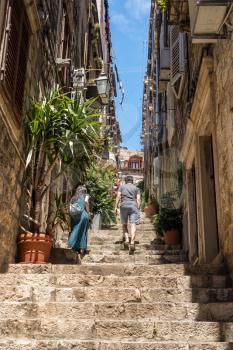 Tourists climbing steep steps in narrow street in the old town of Dubrovnik in Croatia