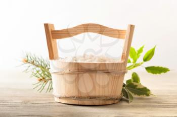 Aromatic bath salt in wooden bucket and green leaves