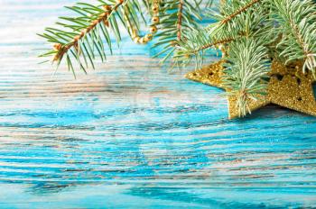 Golden Christmas decoration and fir branch on a blue wooden background