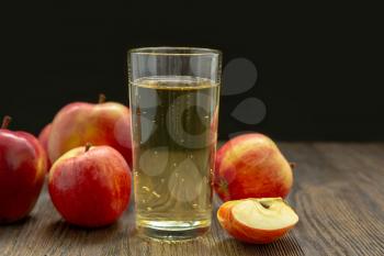 Hard apple cider in a glass and red ripe apples on a black background