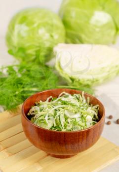 Fresh vegetable salad with cucumber and white cabbage in a wooden plate.  Vegetarian and healthy diet food concept. 