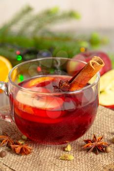 Mulled wine with spices and fruit on a wooden table. Christmas hot drink with red wine, apples, oranges and cinnamon. Tradition holiday menu.