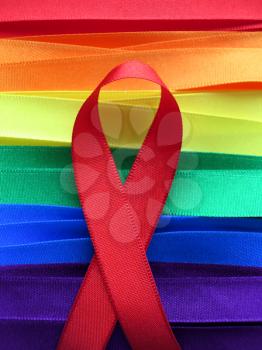 AIDS awareness red ribbon on gay flag background