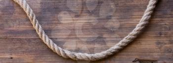 wooden board with a rough texture and a rope with a knot. Blank space for text