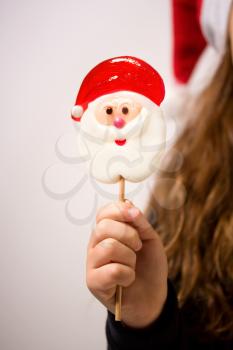 bright New Year's candy in the form of Santa Claus in the foreground in the hand of a little girl