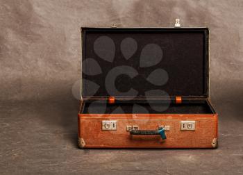 Old long out of fashion redhead open empty suitcase on gray background