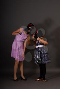 Two teenage hooligans in bright smart dresses, but in gangster balaclava hats with weighty batons whisper about something on a dark background