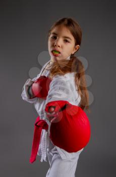 karate girl in kimono and red gloves for the fight with a protective mouthguard for a dark background