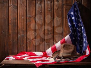 Classic cowboy hat lasso and horseshoe lie on a star-striped USA flag on a dark wooden background