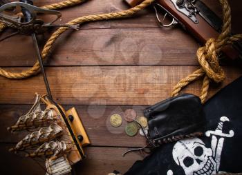 Background of several pirate items lying on a dark wooden surface forming a frame