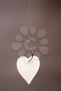 A large classic fishing hook on which a stylized heart hangs a symbol of love