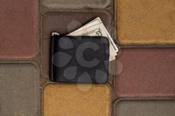 old lost wallet with a few dollar bills wallowing on the sidewalk