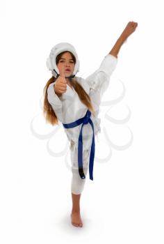 karate girl in a protective helmet with a blue belt and a white kimono with a capa in her lips smiling shows her thumb that everything is fine.