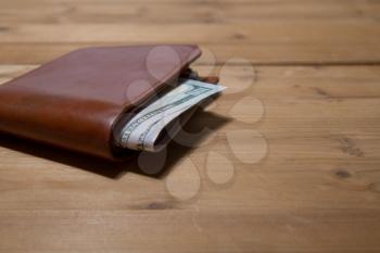 leather brown wallet with five hundred dollars on a wooden surface