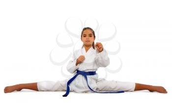 little karate girl in a white kimono and a blue belt sits for a workout in sports twine