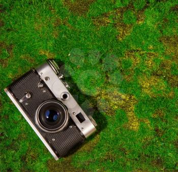 An old camera lies on green grass or moss. View from above