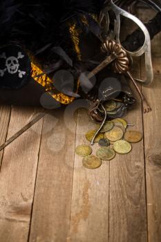pirate hat, sword and wallet with little things on a rustic wooden table