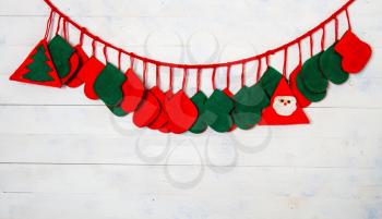 Many Christmas red and green socks for gifts hung on a light wooden wall.