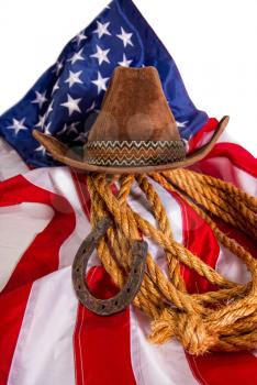 cowboy hat, lasso and horseshoe lying on the usa flag isolated on white background