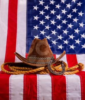 cowboy hat, lasso and horseshoe lying on the usa flag