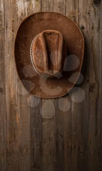 old classic wide-brimmed cowboy brown hat hanging on a rough wooden wall