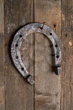 an old horse horseshoe nailed happily by a rusty nail to a wooden wall