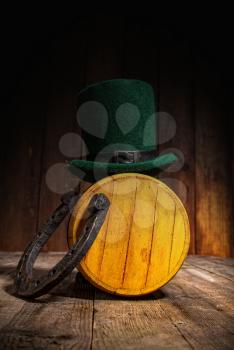 Green leprechaun hat stands on a small wooden barrel with beer in an Irish pub for St. Patrick's Day.