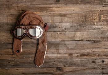 kids toy pilot glasses and brown helmet on old wooden background