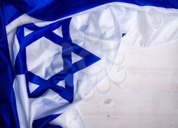White-blue Israeli state flag with a star of David lies on wooden boards forming a frame for text