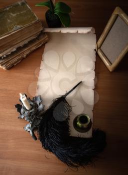Empty paper scroll with place for text, ostrich feather for writing and a stack of old books with photo frame