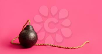 classic round black antique bomb with a long non-burning rope wick on a pink background